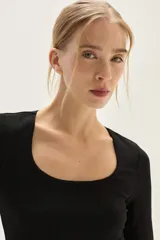 Top negro de manga larga, confeccionado en tela de lurex con calce al cuerpo y escote cuadrado.