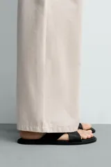Sandalia plana de diseño minimalista con dos tiras anchas cruzadas en el empeine y suela a tono.