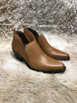 Botín de cuero color bordó, con caña baja, corte en V en el tobillo y taco de madera.