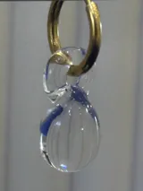 Aros de argolla dorada con dije colgante de vidrio de Murano transparente con vetas azules y textura estriada.