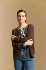 Cardigan de punto color terracota con diseño de trenzas verticales, cuello redondo y cierre frontal con botones metálicos. Presenta mangas largas con puños ajustados y un calce holgado.