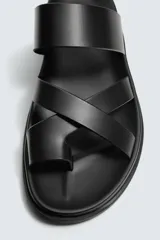 Sandalia plana negra con tiras anchas cruzadas sobre el empeine y una tira que separa el dedo gordo. Posee plantilla anatómica.