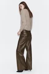 Pantalón de tiro medio confeccionado en tejido efecto piel, con diseño de cinco bolsillos y cierre frontal con cremallera y botón.