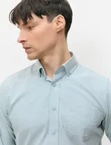Camisa de manga larga de tejido Oxford color celeste, con cuello button-down, cierre frontal de botones y un bolsillo aplicado en el pecho.