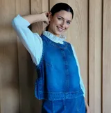 Chaleco de corte recto y largo a la cintura, confeccionado en denim con estampado de rayas verticales en tonos azul y blanco. Presenta cuello redondo y costuras visibles que definen su estructura.