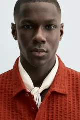 Polo de hombre color terracota con cuello solapa y cierre frontal de botonadura. Presenta un tejido texturizado tipo seersucker y un calce relajado.