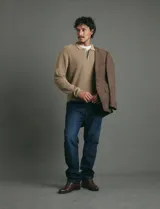 Remera de punto tipo polo color beige, con cuello camisero, cierre frontal parcial con botones y mangas largas.