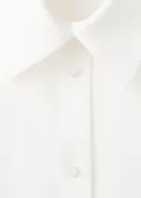 Camisa blanca de lyocell, con cuello solapa, mangas largas y detalle cruzado o de cinturón simulado en la cintura.