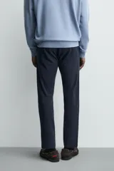 Pantalón chino de corte ajustado, color beige, con bolsillos laterales y bolsillos traseros de vivo. Cuenta con cierre frontal de cremallera y botón.