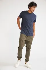 Pantalón cargo de corte slim, color verde oliva, con bolsillos laterales tipo cargo, cierre frontal con botón y puños elásticos en los tobillos.