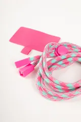 Correa para celular con diseño geométrico en tonos rosa y celeste, con aplique de plástico rosa. Incluye parche de tela rosa para sujetar al celular.
