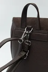 Mochila estructurada color marrón oscuro, con frente en acabado gamuzado y cuerpo en símil cuero texturizado. Tiene asa superior y correas regulables.