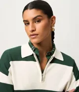 Suéter de punto color verde oscuro y blanco, con cuello polo, cierre frontal parcial de cremallera metálica y mangas largas con puños. Presenta un estampado de rayas horizontales.