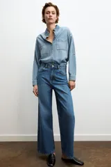 Jeans de tiro alto con diseño de pierna ancha y cinco bolsillos. Cuenta con cierre frontal mediante cremallera y botón metálico.