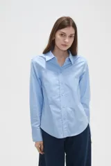 Camisa de algodón blanca, de corte entallado al cuerpo, con cuello camisero, manga larga y cierre frontal de botones.