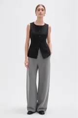 Chaleco sin mangas de corte sastrero, color marrón con diseño de rayas verticales finas. Presenta cuello redondo, cierre frontal con botones y dos bolsillos laterales simulados.