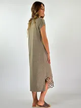 Vestido midi de tejido de punto color marrón, con cuello en V y mangas cortas. Presenta un diseño holgado y un detalle decorativo de crochet con formas circulares en el ruedo.