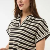 Remera tipo polo de manga corta con patrón de rayas horizontales en color negro y beige, escote en V y cuello clásico.
