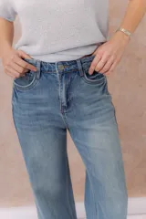 Pantalón de jean azul claro, con tiro medio-alto, corte wide leg y diseño de cinco bolsillos.