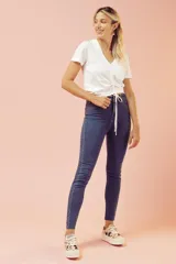 Jeans ajustados de tiro alto en tono azul oscuro, con diseño clásico de cinco bolsillos y terminación desmechada en los tobillos.