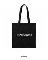 Tote bag negra de lona con estampado gráfico estilo graffiti en color blanco en el frente. Cuenta con dos asas largas para llevar al hombro.