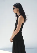 Vestido midi negro sin mangas, con cuello redondo, fruncidos en el cuerpo y falda de corte evasé.
