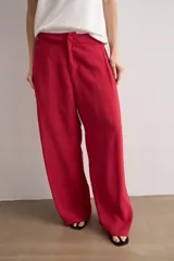 Pantalón de corte recto y pinzas delanteras, color rojo, con bolsillos laterales y cierre frontal con botón y cremallera.