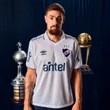Camiseta de fútbol Umbro del Club Nacional de Football, modelo Home 2026, para hombre. Diseño en color blanco con detalles en azul y rojo en el cuello y los bordes de las mangas. Incluye el logo de Umbro, el escudo del club y el sponsor Antel en el frente.
