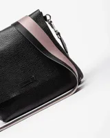 Bandolera color beige con correa ancha de tela negra con el nombre de la marca en blanco.