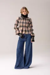 Blusa de manga larga con diseño a cuadros en tonos beige y negro. Presenta un cuerpo con fruncido elástico tipo nido de abeja, cuello alto con volado y mangas abullonadas con puños elásticos y terminación acampanada.