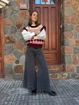 Chaleco tejido de punto con diseño multicolor en bloques, cuello redondo y terminaciones acanaladas. Presenta un patrón geométrico en tonos bordó, rosa, celeste, marrón y crema.