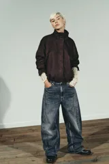 Chaqueta bomber color marrón oscuro con efecto ante, cuello subido y manga larga con puños. Tiene bolsillos delanteros, bajo con pliegues y volumen, forro interior y cierre frontal con cremallera y botones a presión ocultos.