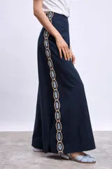 Pantalón palazzo azul marino con apliques bordados de hojas en los laterales.