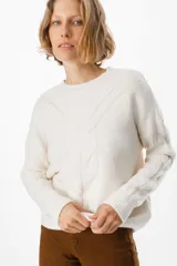 Sweater de punto negro con diseño de trenzas verticales en el frente y cuello redondo. Presenta un corte holgado con puños y ruedo acanalados.