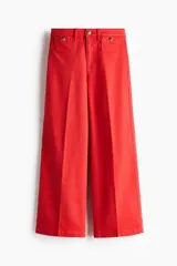Jean rojo de tiro alto, corte wide leg y diseño tobillero, con bolsillos delanteros tipo parche con botón y pliegues marcados.