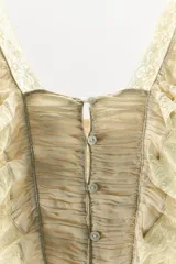 Vestido largo color beige de viscosa, con escote cuadrado, tirantes anchos, detalles drapeados, volantes y aplicaciones de encaje a contraste en el pecho. Cuenta con cierre trasero de botones.