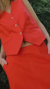 Chaleco plateado con cuello en V, cierre frontal con botones y bolsillos delanteros.