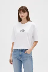 Remera de manga corta color blanco con cuello redondo y diseño holgado, con estampa pequeña de un auto en el pecho.