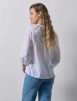 Blusa blanca de gasa bambula marca Zac & Rachel, con cuello a la base y apertura central con botones. Presenta apliques de puntilla en la parte delantera y en las mangas ¾ con terminación fruncida.