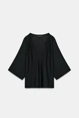 Top de punto fluido color negro, con escote en V pronunciado y mangas cortas amplias.