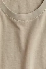 Remera color beige de corte recto en punto suave de algodón con cuello redondo ribeteado y hombros ligeramente caídos.