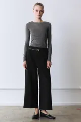 Pantalón culotte negro de tiro medio con trabillas y cinturón fino efecto piel con hebilla metálica. Presenta raya planchada y cierre de cremallera oculta en la costura.