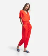 Pantalón jogger color naranja, de tiro medio, con cintura elastizada, lazo ajustable, pliegues delanteros y bolsillos laterales.
