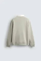 Sudadera de manga larga estilo polo con diseño de rayas horizontales anchas en azul marino y blanco. Presenta cuello de solapa en contraste, cierre frontal con botones ocultos y acabados en rib en puños y bajo.