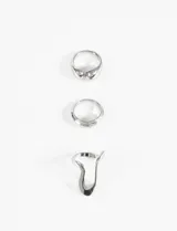 Set de tres anillos de metal plateado con diseños irregulares y orgánicos, de estilo minimalista y moderno.