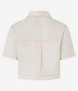 Camisa cropped de sarga color crudo, con cuello clásico, cierre frontal con botones dorados, manga corta, bolsillo de parche en el pecho y costuras a contraste. Confeccionada con algodón certificado.