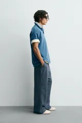 Polo de algodón con estructura piqué, color azul deslavado. Presenta un corte regular fit, cuello solapa con cierre de botones, manga corta con acabado en rib y bajo asimétrico con aberturas laterales.