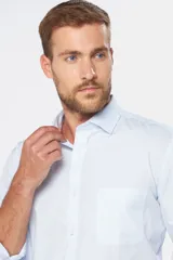 Camisa de vestir blanca de manga larga, con cuello clásico y cierre frontal de botones.
