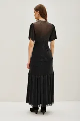 Vestido midi de color negro con acabado brillante, escote en V cruzado, mangas cortas con volados y falda con niveles fruncidos.