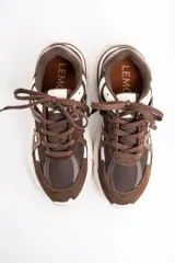 Zapatilla urbana de diseño robusto, confeccionada en una combinación de malla, gamuza y detalles en cuero sintético. Presenta una paleta de colores en tonos chocolate y crema, con suela dentada de goma de gran volumen.